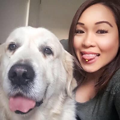 A woman and a large white dog posing for a selfie, both looking at the camera with tongues playfully sticking out.